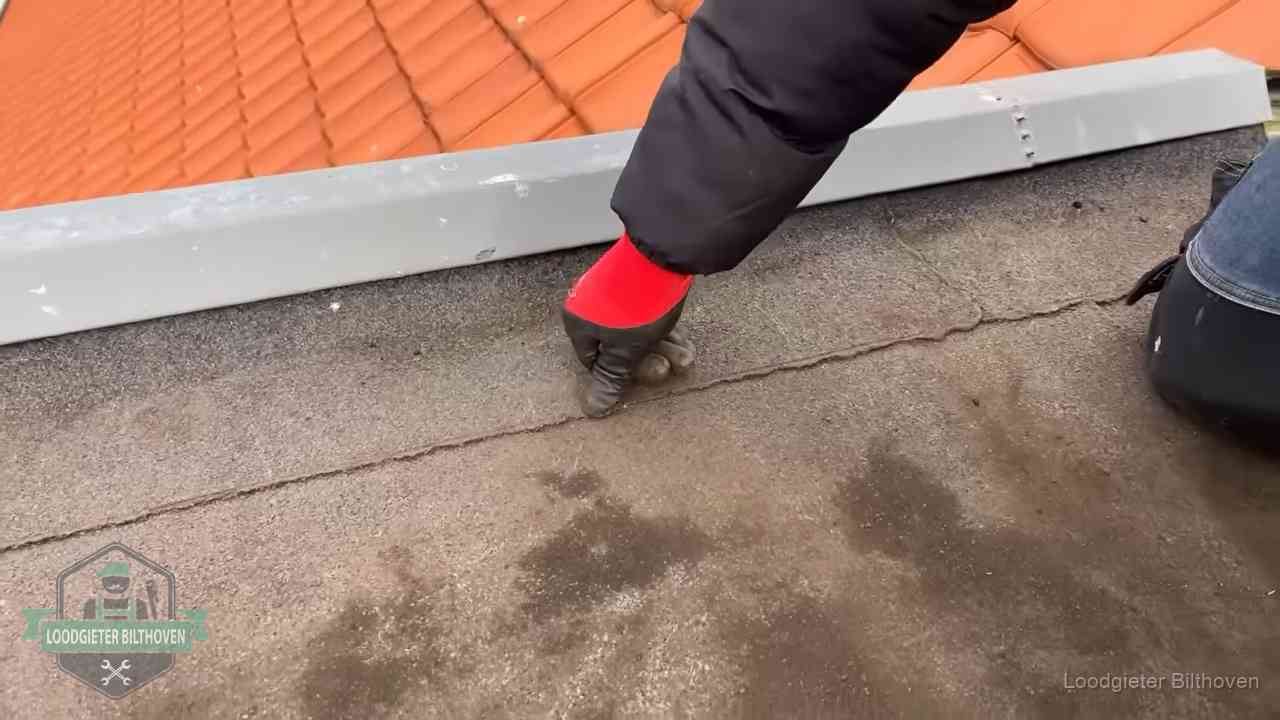 Lekkage bij de naad van een plat dak in Bilthoven Vakman wijst een naad met vochtplekken aan op een bitumen plat dak in Bilthoven