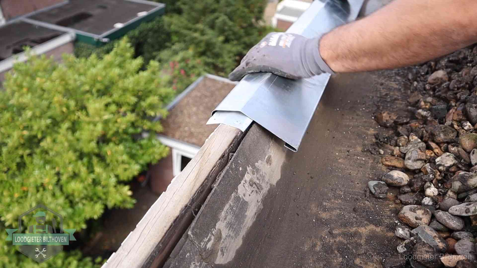 Daklekkage per wijk in Bilthoven Dakdekker plaatst een zinken deklijst op een dakrand met uitzicht over een woonwijk in Bilthoven