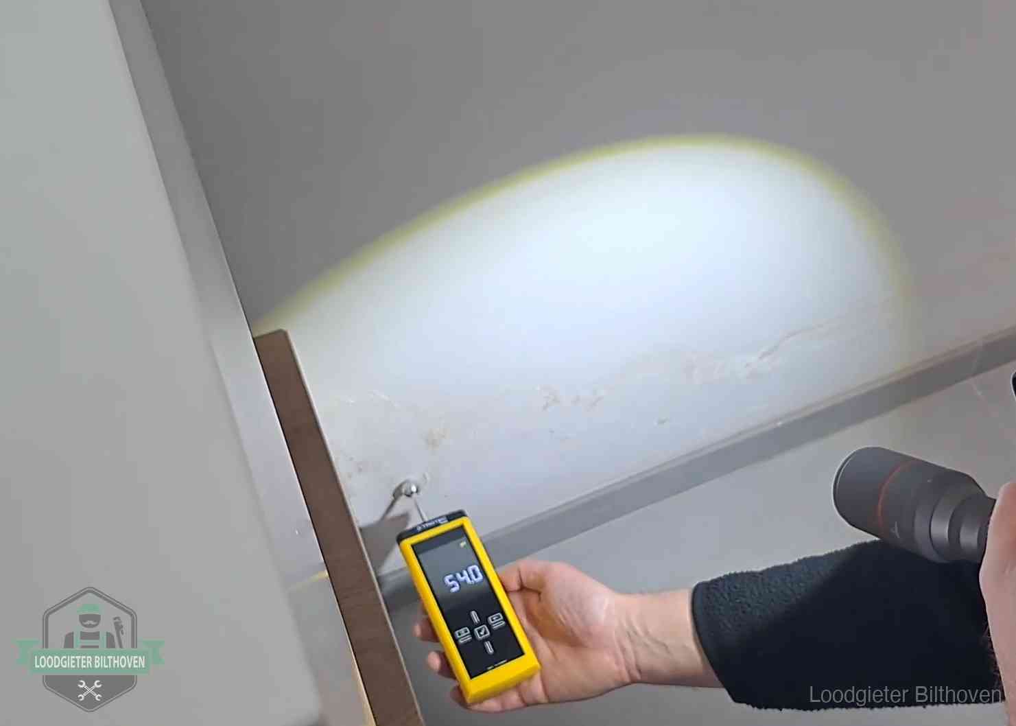 Vochtmeter tegen een natte wand met lekkagesporen in Bilthoven