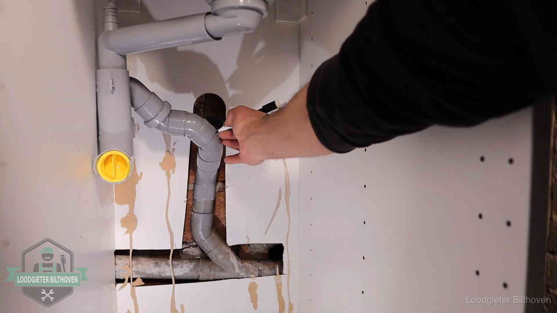 Loodgieter markeert een pvc-afvoerbuis onder een gootsteen in Bilthoven