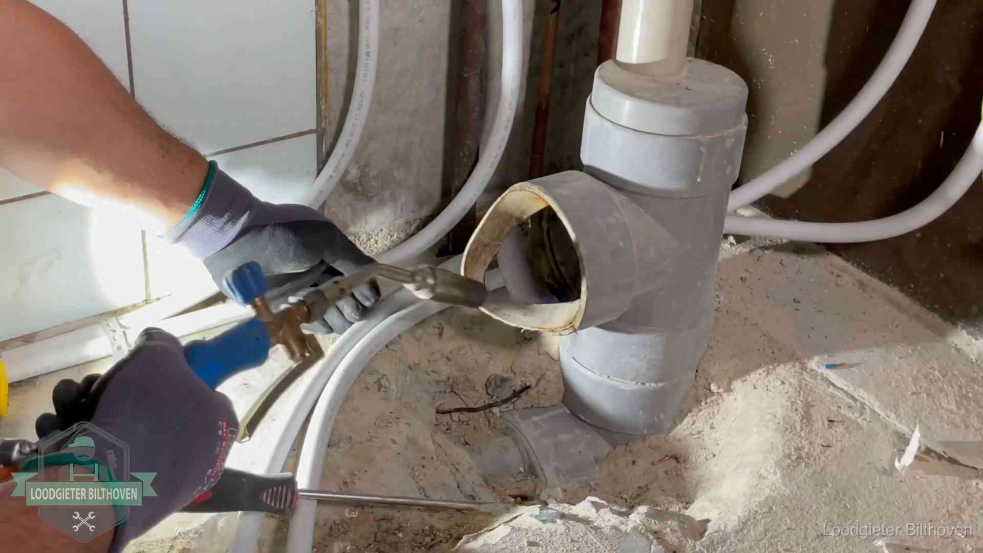 Loodgieter werkt met brander en messing kraanwerk aan leidingen in Bilthoven