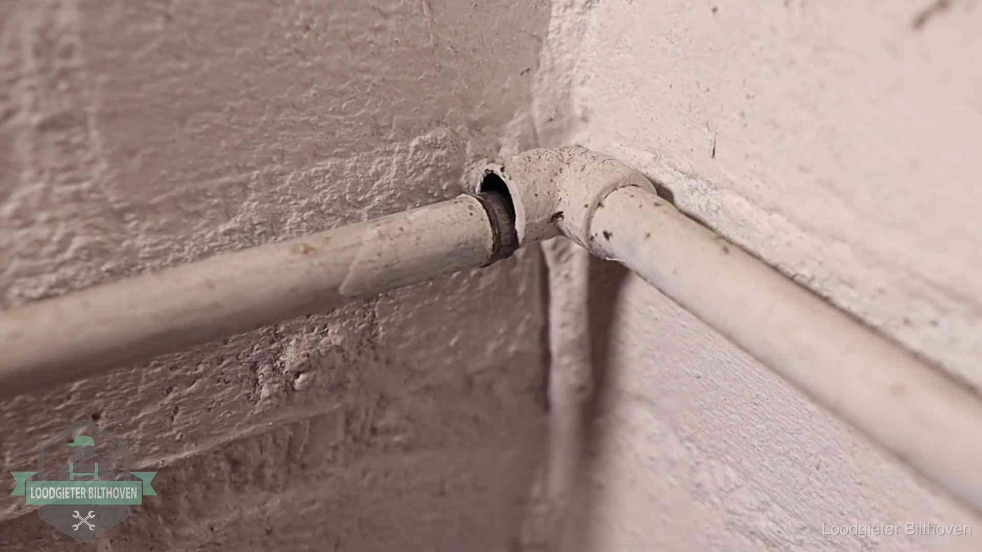 Oude geverfde waterleiding met een losliggende fitting in een woning in Bilthoven