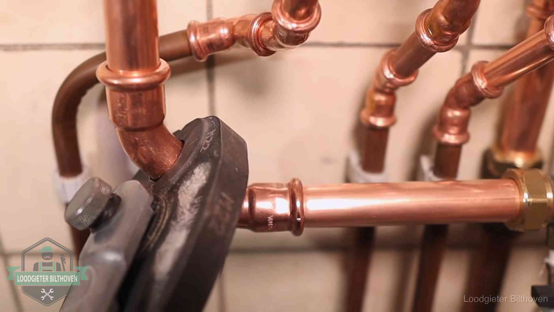 Persmachine perst een koperen fitting op nieuw leidingwerk in Bilthoven
