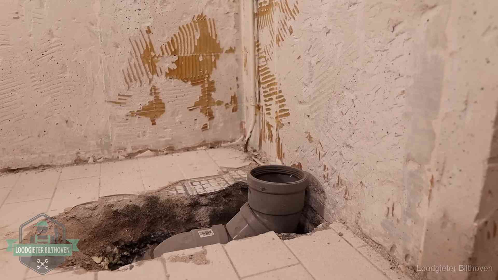 Verzakt riool herstellen in Bilthoven Opengebroken vloer met een nieuwe pvc-rioolbocht in een gegraven sleuf in Bilthoven